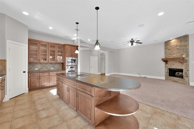 kitchen with stainless steel appliances, dark countertops, glass insert cabinets, open floor plan, and a kitchen island