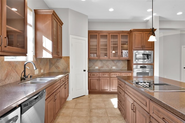 kitchen featuring stainless steel appliances, a sink, dark countertops, glass insert cabinets, and pendant lighting