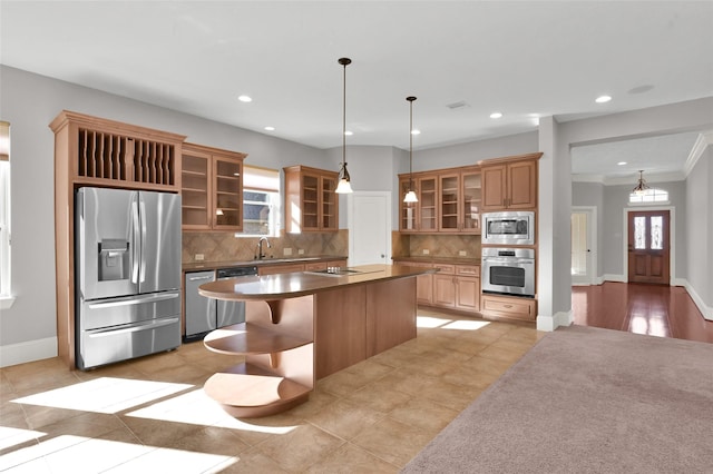 kitchen featuring stainless steel appliances, a kitchen island, hanging light fixtures, dark countertops, and glass insert cabinets