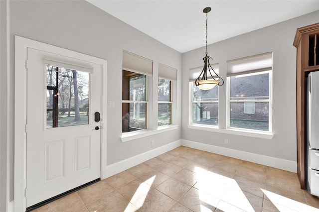 unfurnished dining area with light tile patterned floors and baseboards