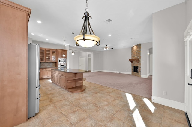 kitchen featuring decorative light fixtures, dark countertops, glass insert cabinets, appliances with stainless steel finishes, and open floor plan