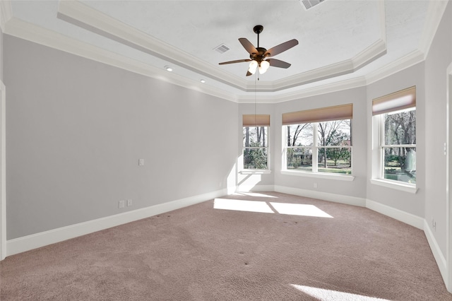 spare room with ornamental molding, a tray ceiling, a healthy amount of sunlight, and visible vents