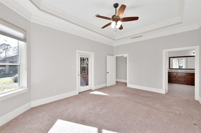 unfurnished bedroom featuring a raised ceiling, visible vents, light carpet, and multiple windows