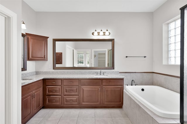 bathroom with a garden tub, double vanity, a sink, and tile patterned floors