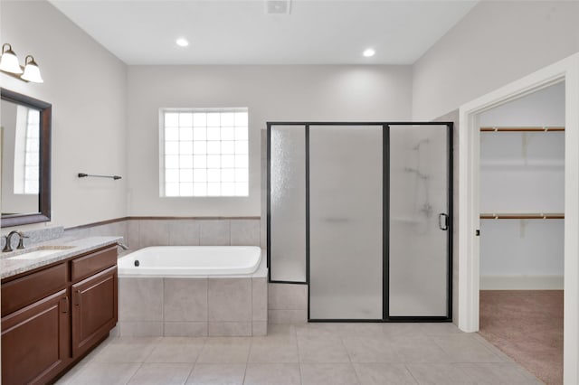 bathroom with a walk in closet, tile patterned flooring, a shower stall, and a bath