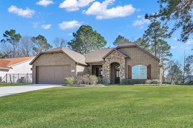 french provincial home featuring a garage, concrete driveway, stone siding, a front yard, and brick siding