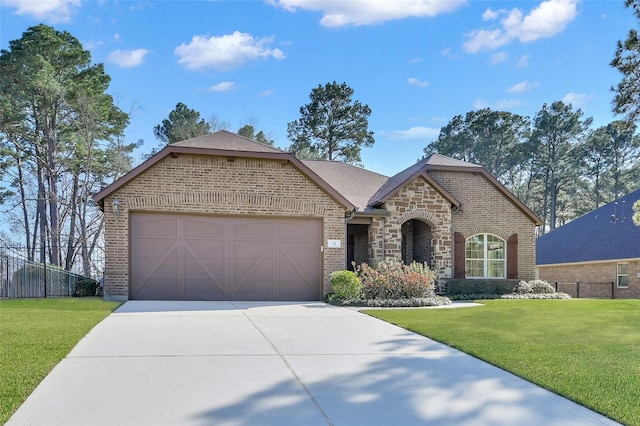 french country home with brick siding, an attached garage, fence, driveway, and a front lawn