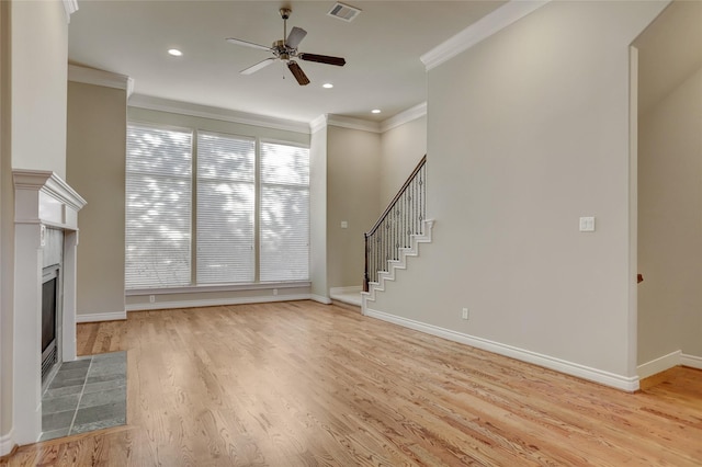 unfurnished living room featuring visible vents, light wood-style flooring, stairway, ornamental molding, and a tile fireplace