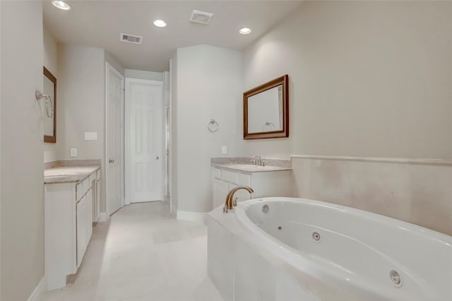 bathroom with a tub with jets, visible vents, and vanity