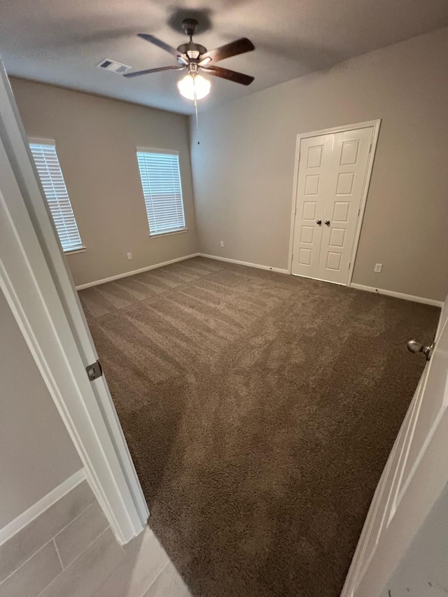 unfurnished bedroom with carpet, visible vents, and baseboards