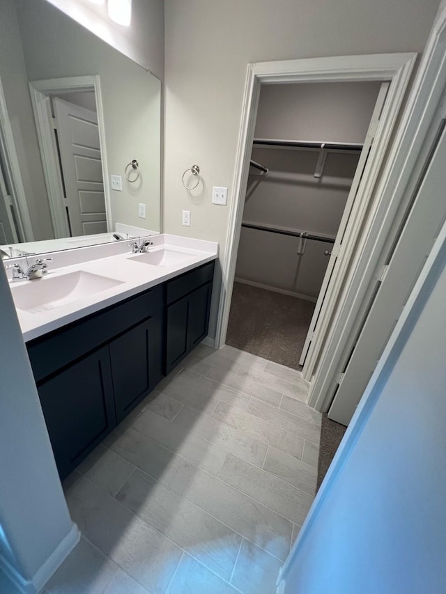 bathroom featuring double vanity, a walk in closet, and a sink