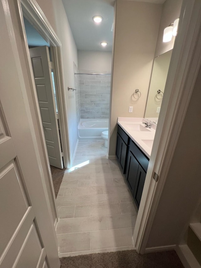 bathroom featuring toilet, baseboards, tub / shower combination, and vanity