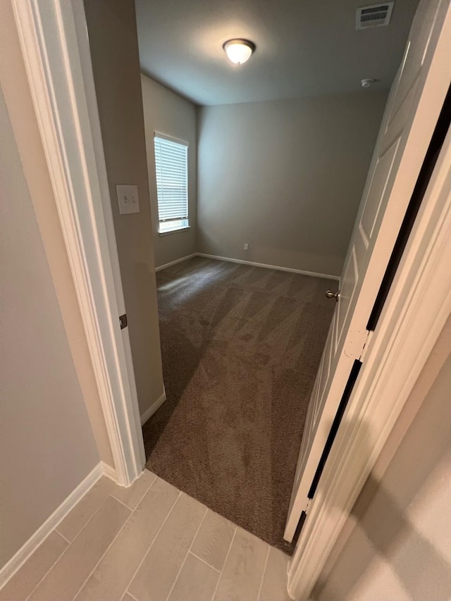 corridor with light carpet, baseboards, and visible vents