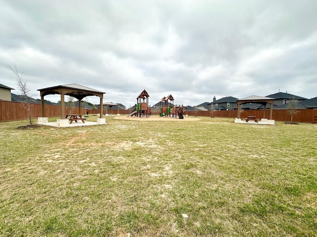 view of yard with a gazebo, an outdoor fire pit, playground community, and a fenced backyard