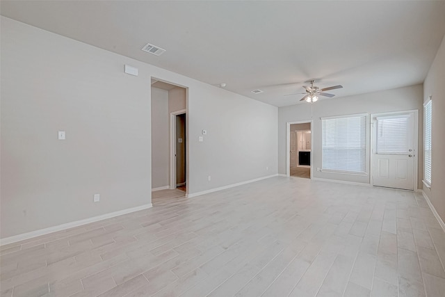 unfurnished room featuring light wood-type flooring, ceiling fan, visible vents, and baseboards