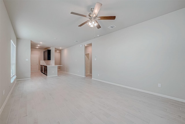 unfurnished living room with light wood finished floors, ceiling fan, visible vents, and baseboards