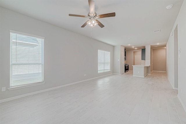 unfurnished living room featuring light wood finished floors, visible vents, baseboards, and a ceiling fan