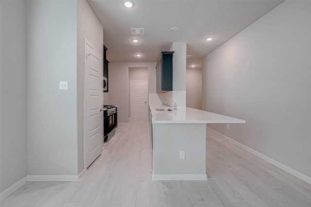 kitchen with light wood finished floors, stainless steel appliances, light countertops, visible vents, and a sink