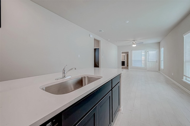 kitchen with a ceiling fan, open floor plan, light countertops, and a sink