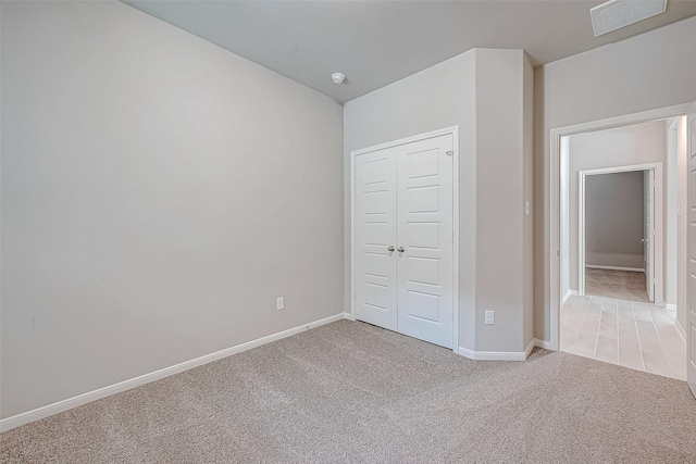 unfurnished bedroom featuring light carpet, a closet, visible vents, and baseboards