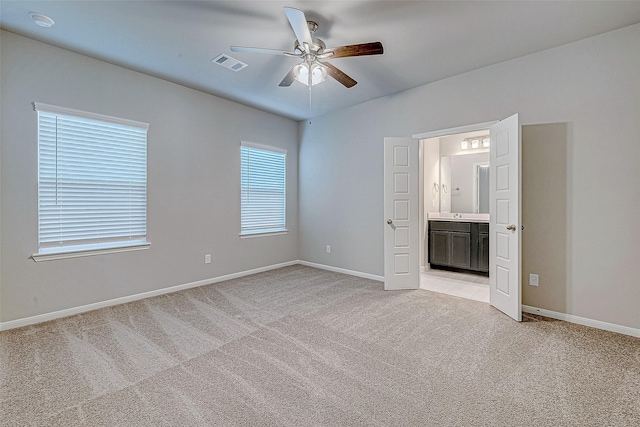 unfurnished bedroom featuring light carpet, baseboards, visible vents, ceiling fan, and ensuite bathroom