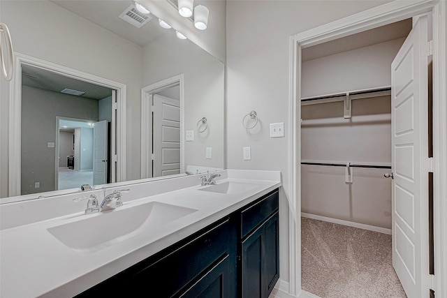 full bath with a spacious closet, double vanity, a sink, and visible vents