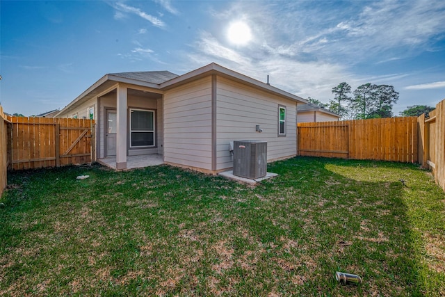 rear view of property with a fenced backyard, a gate, a lawn, and central AC