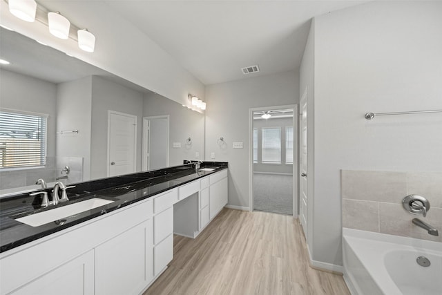 full bath featuring double vanity, visible vents, a sink, and wood finished floors