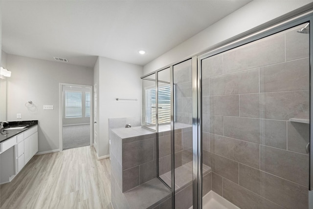 full bath with wood finished floors, vanity, visible vents, baseboards, and a stall shower