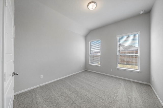 empty room featuring carpet flooring, vaulted ceiling, and baseboards