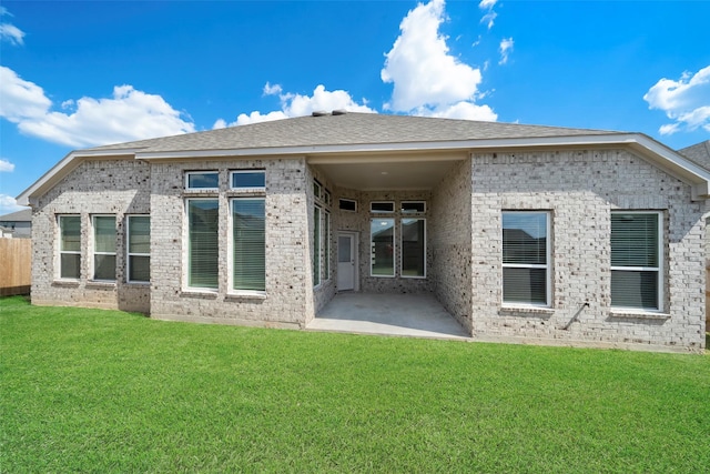 back of property featuring a patio, brick siding, a lawn, and roof with shingles