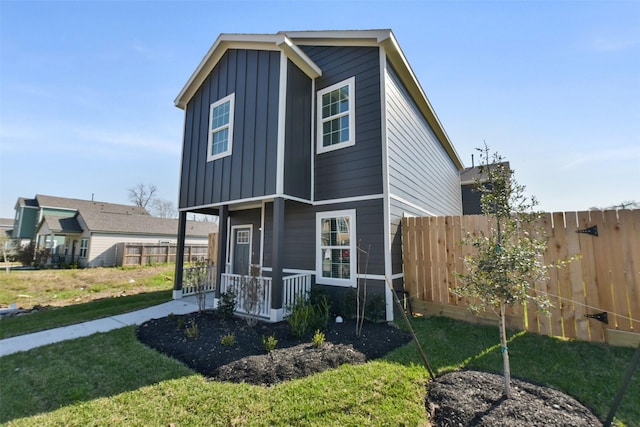 view of front of home with a porch, board and batten siding, a front yard, and fence