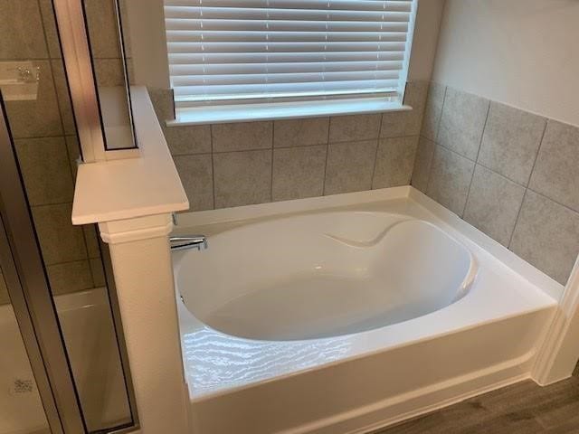 bathroom featuring a shower stall and a bath