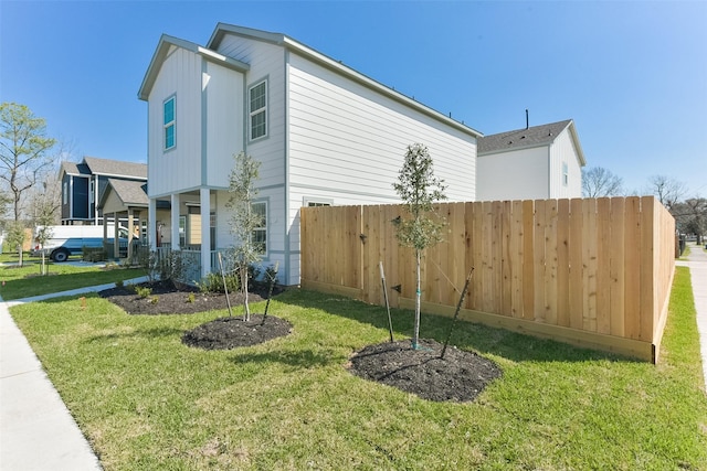 view of side of home with a yard, a porch, and fence