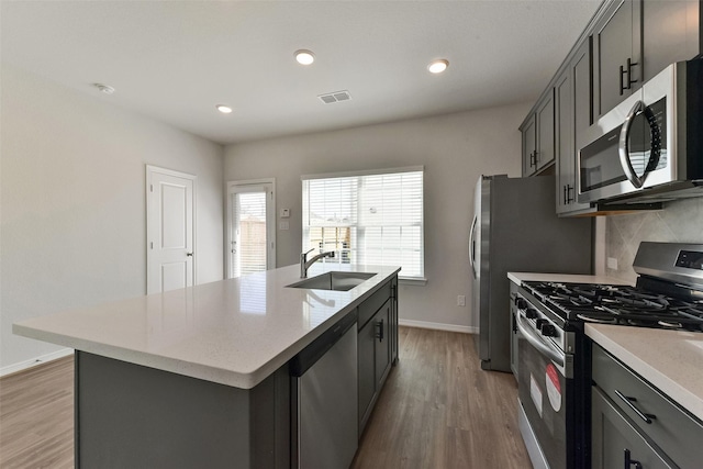 6835 New York St, Houston, TX 77021 - kitchen with stainless steel appliances, tasteful backsplash, light wood-style floors, a sink, and an island with sink