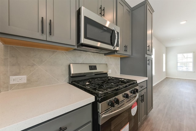 6835 New York St, Houston, TX 77021 - kitchen with light wood finished floors, appliances with stainless steel finishes, backsplash, and gray cabinetry