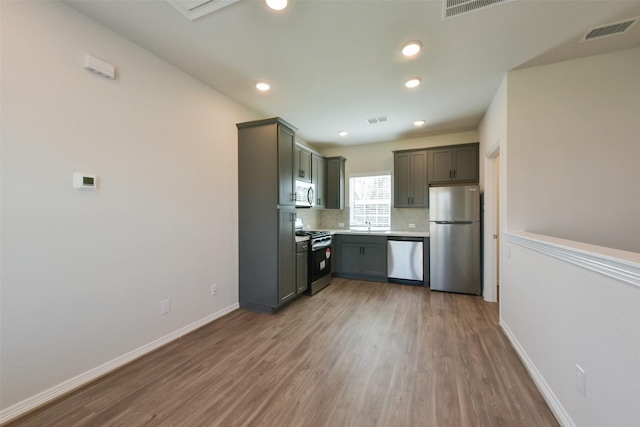 6835 New York St, Houston, TX 77021 - kitchen with stainless steel appliances, visible vents, backsplash, and wood finished floors