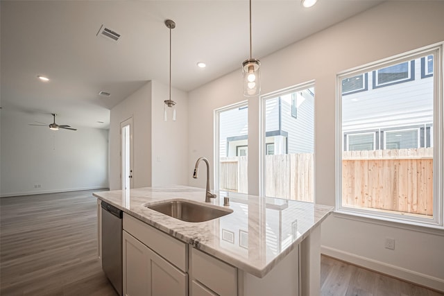 kitchen featuring visible vents, light stone counters, decorative light fixtures, a sink, and stainless steel dishwasher