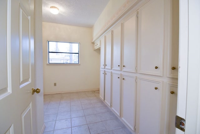 hall featuring light tile patterned flooring and a textured ceiling