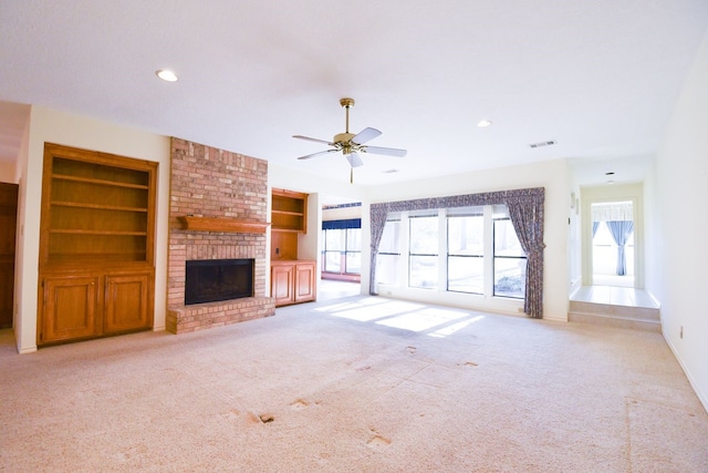 unfurnished living room featuring built in shelves, recessed lighting, visible vents, a brick fireplace, and light carpet