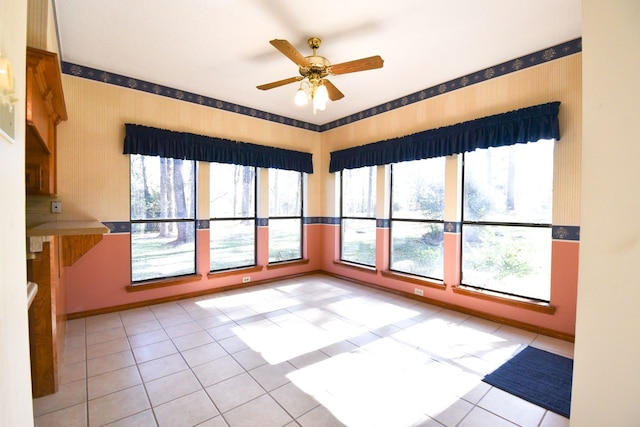 empty room featuring light tile patterned floors, baseboards, and a ceiling fan