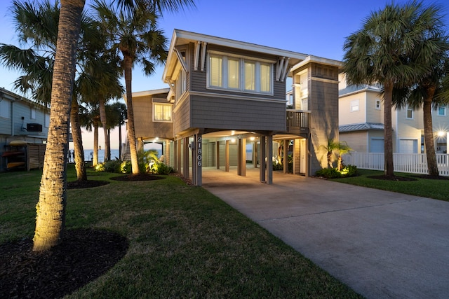 view of front of home with concrete driveway, a carport, a front yard, and fence