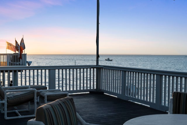 deck at dusk featuring a water view