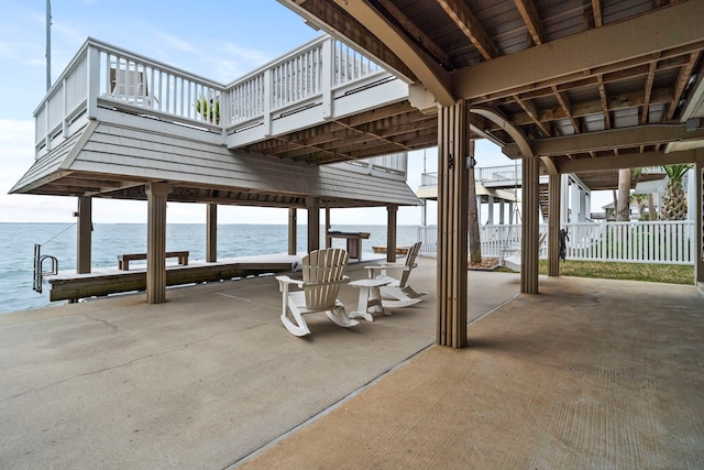 view of patio featuring a water view, a dock, and fence