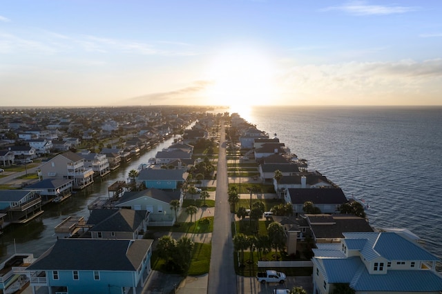 aerial view at dusk with a water view and a residential view