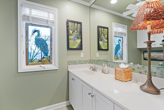 bathroom with a ceiling fan, vanity, baseboards, ornamental molding, and backsplash