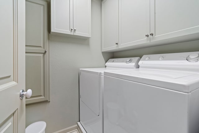 clothes washing area featuring washing machine and dryer and cabinet space