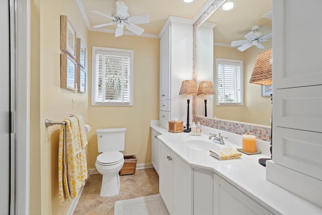 bathroom featuring baseboards, a ceiling fan, toilet, crown molding, and vanity