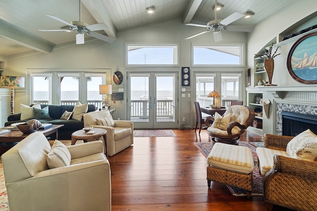 living room with french doors, vaulted ceiling with beams, wood-type flooring, a premium fireplace, and a ceiling fan