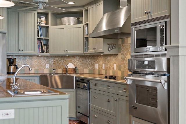 kitchen with appliances with stainless steel finishes, a sink, wall chimney range hood, open shelves, and backsplash